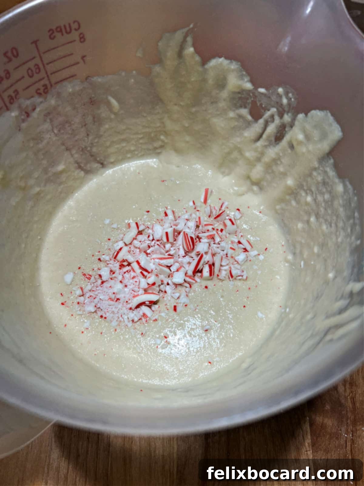 Minty Morning Flapjacks 4 Crushed red and white candy canes being stirred into a bowl of light-colored pancake batter.