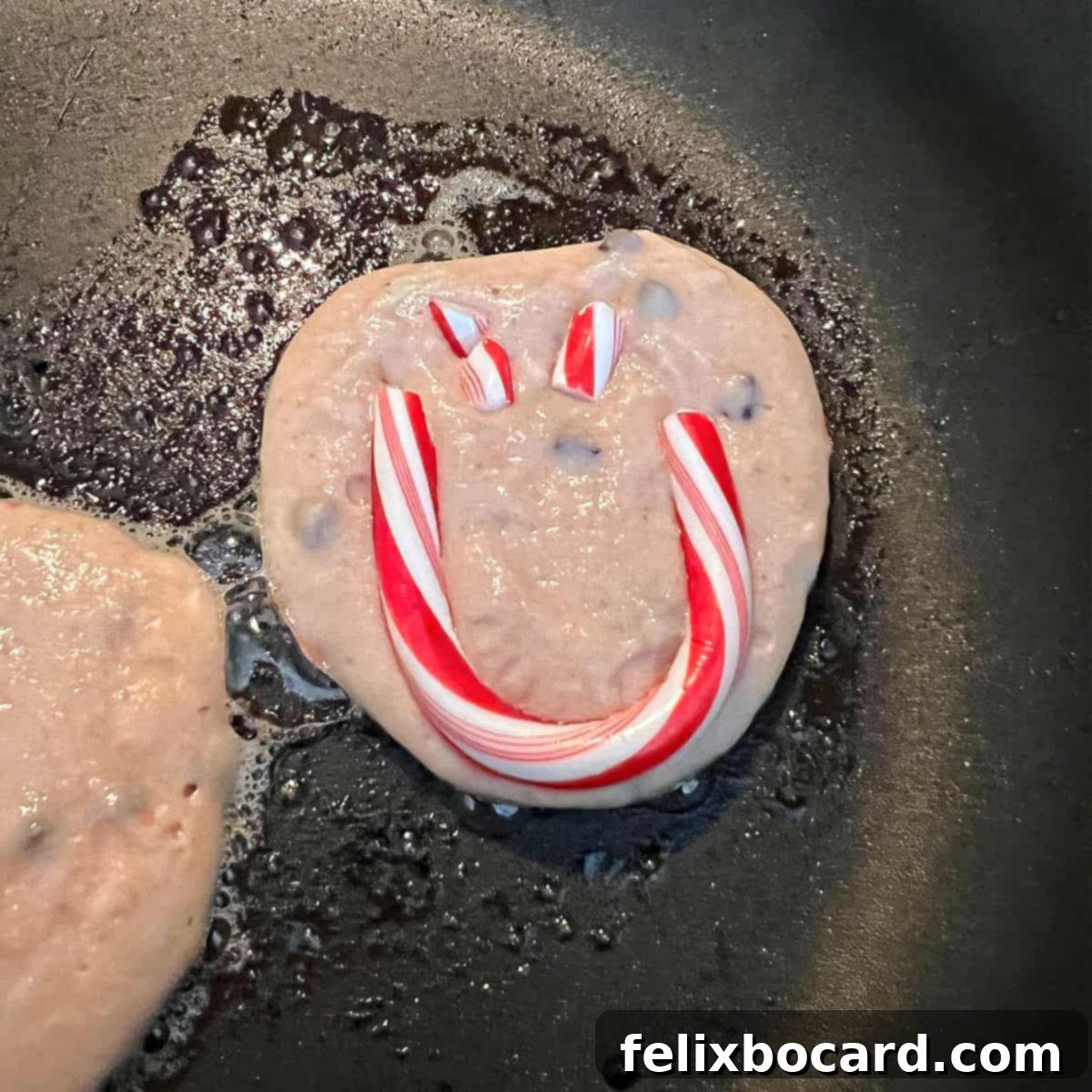 Minty Morning Flapjacks 5 Two peppermint pancakes with faint smiley faces cooking on a hot griddle, bubbles forming on the surface.