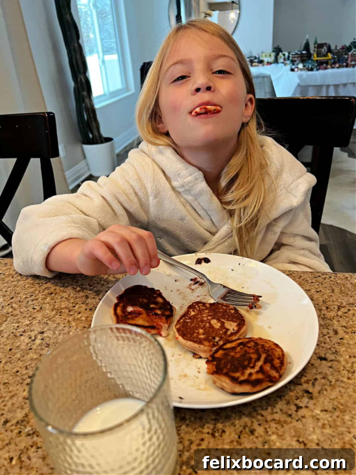 Minty Morning Flapjacks 7 A child holds a candy cane smile from a pancake up to their own mouth, creating a playful, matching smile.