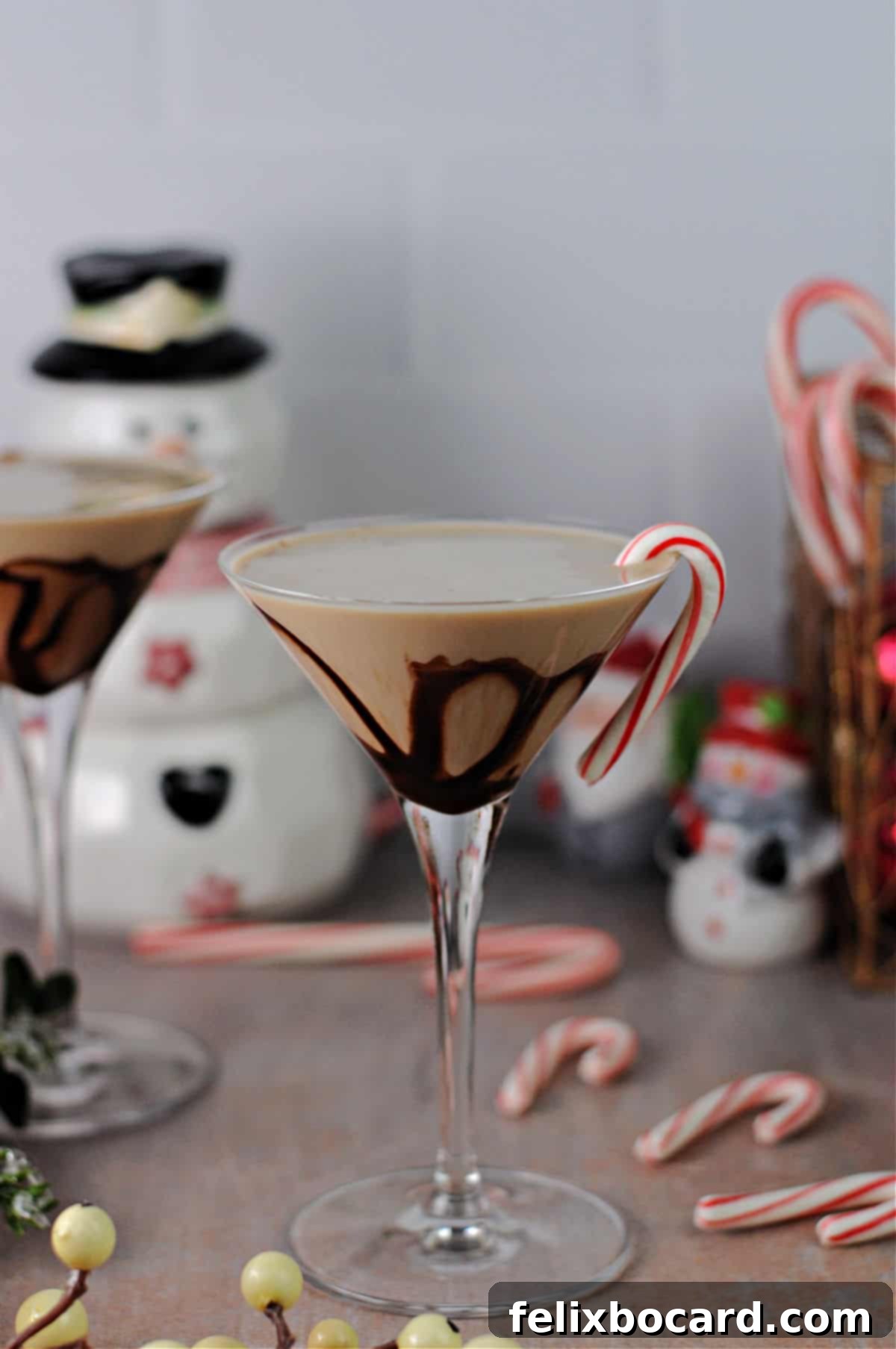 Martini glass filled with a creamy chocolate peppermint cocktail, beautifully garnished with a miniature candy cane and a dusting of cocoa powder.