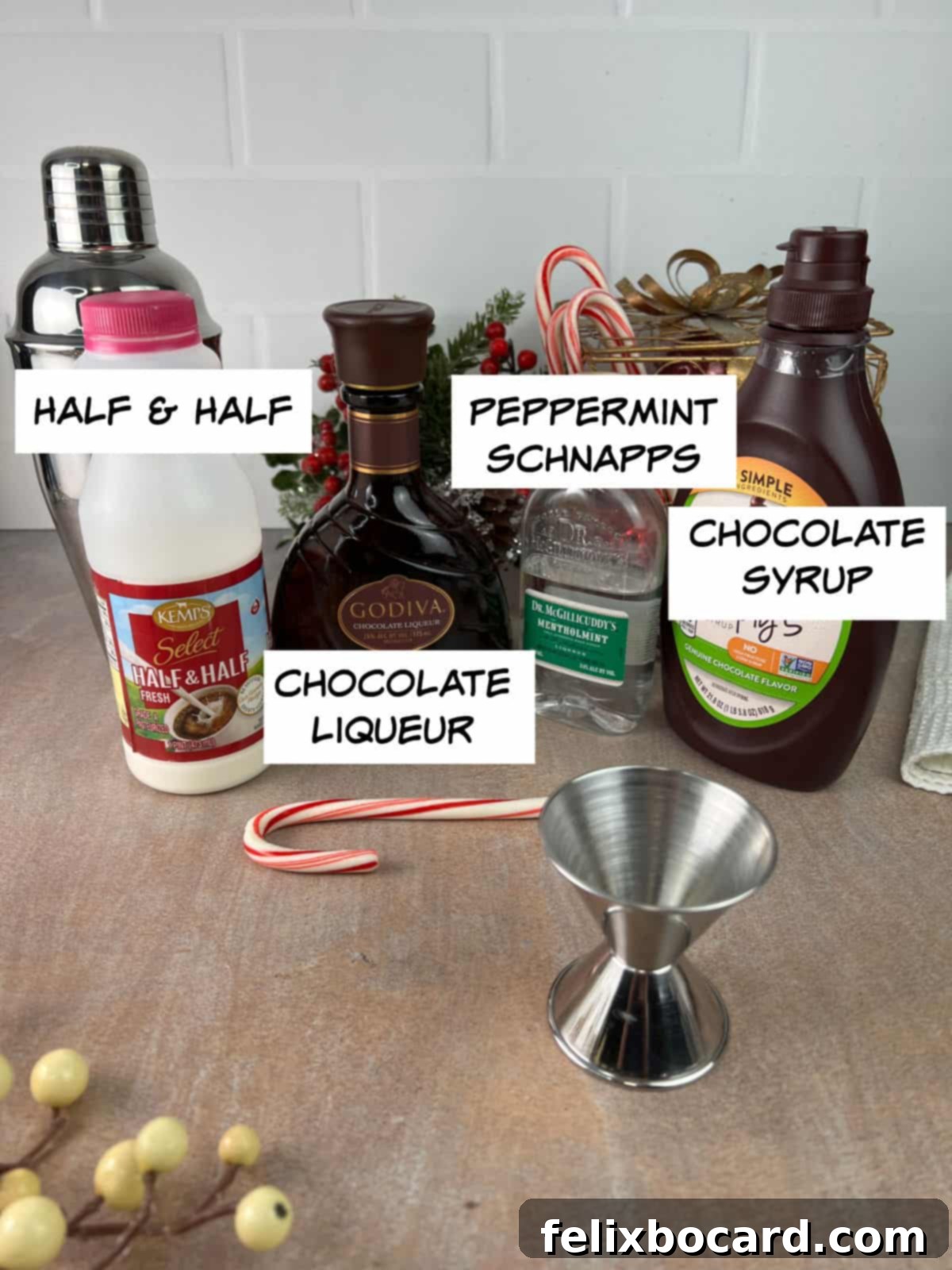 Ingredients for chocolate peppermint martini: a bottle of half & half, a bottle of chocolate liqueur, a bottle of peppermint schnapps, and a bottle of chocolate syrup, arranged neatly on a surface.