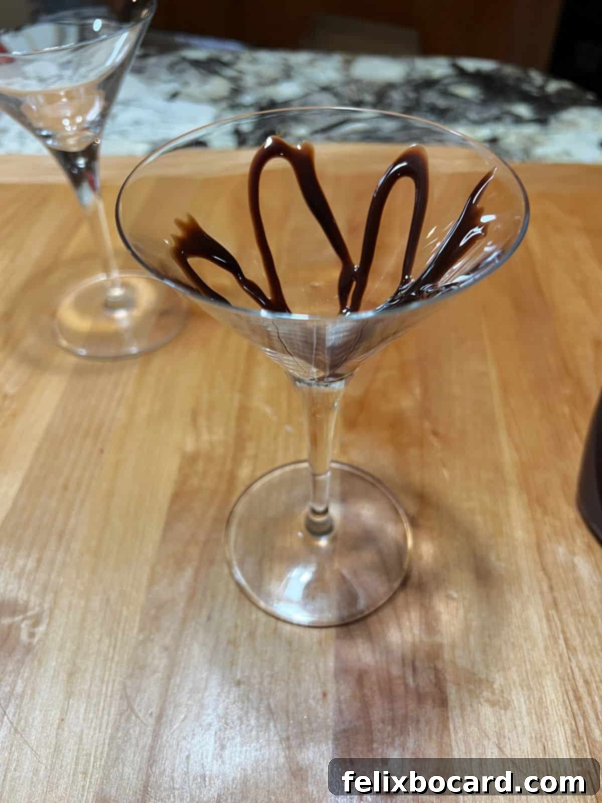 Martini glass expertly drizzled with chocolate syrup, ready for chilling.