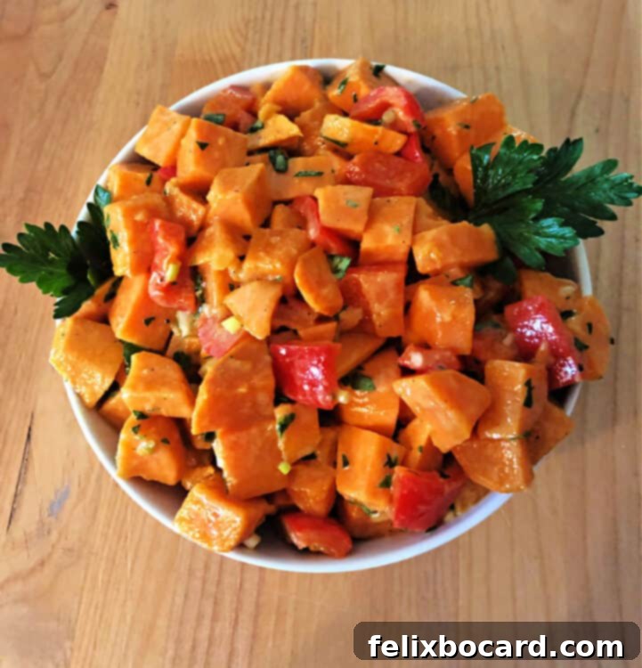 Top down view of sweet potato salad in a white bowl, garnished with fresh herbs.