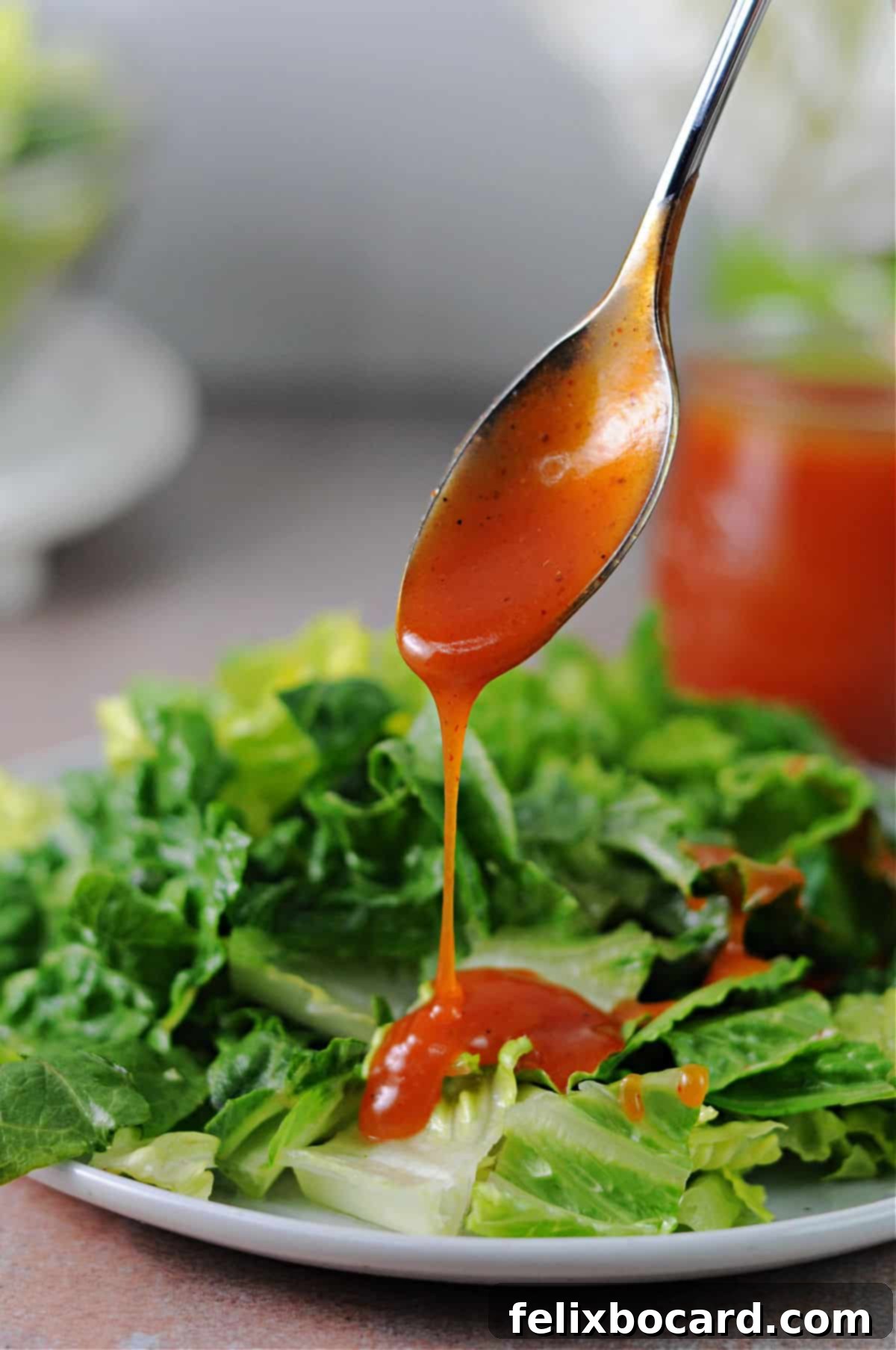 Whip Up Zesty Homemade Catalina Dressing 2 spoonful of sweet catalina dressing pouring onto a lettuce salad.
