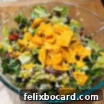 A big bowl of colorful Dorito taco salad, generously dressed with Catalina dressing and topped with crunchy chips.