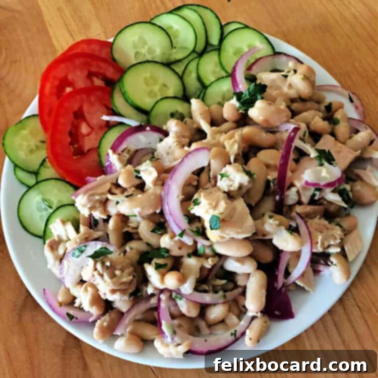 Fresh Tuna Bean Medley 3 Plate of tuna and bean salad with sliced cucumbers and tomatoes on the side, highlighting fresh ingredients.