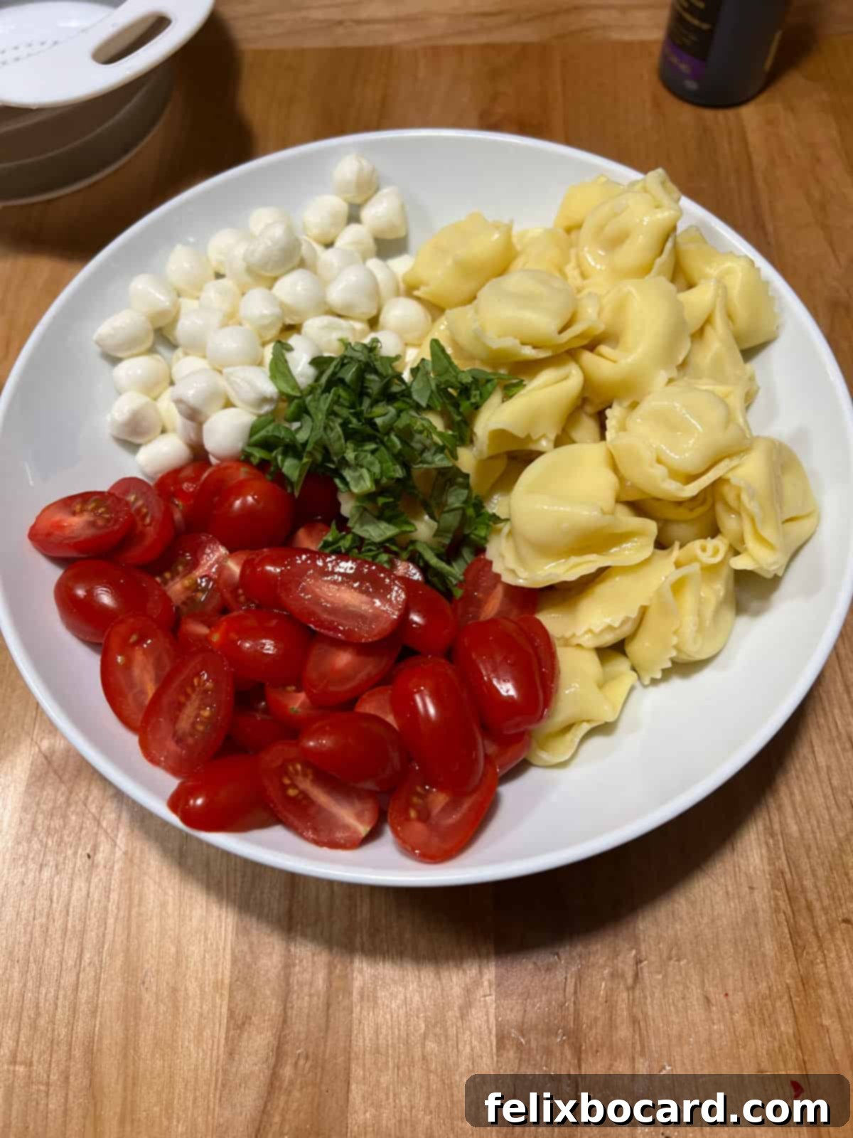 Vibrant Caprese Tortellini Salad 4 The bare ingredients for Caprese tortellini salad in a bowl: cooked tortellini, halved grape tomatoes, fresh mozzarella, and thinly sliced basil, ready for dressing.