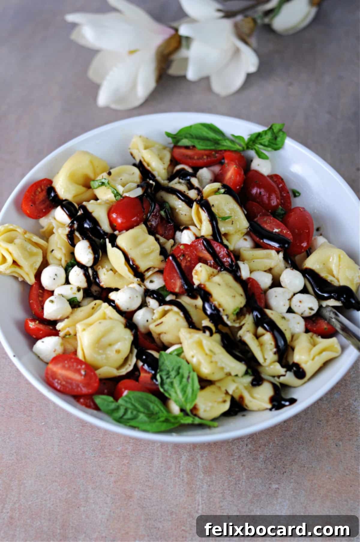 Vibrant Caprese Tortellini Salad 6 A beautifully completed Caprese tortellini pasta salad, glistening with balsamic glaze and garnished with fresh basil leaves, ready to be enjoyed.