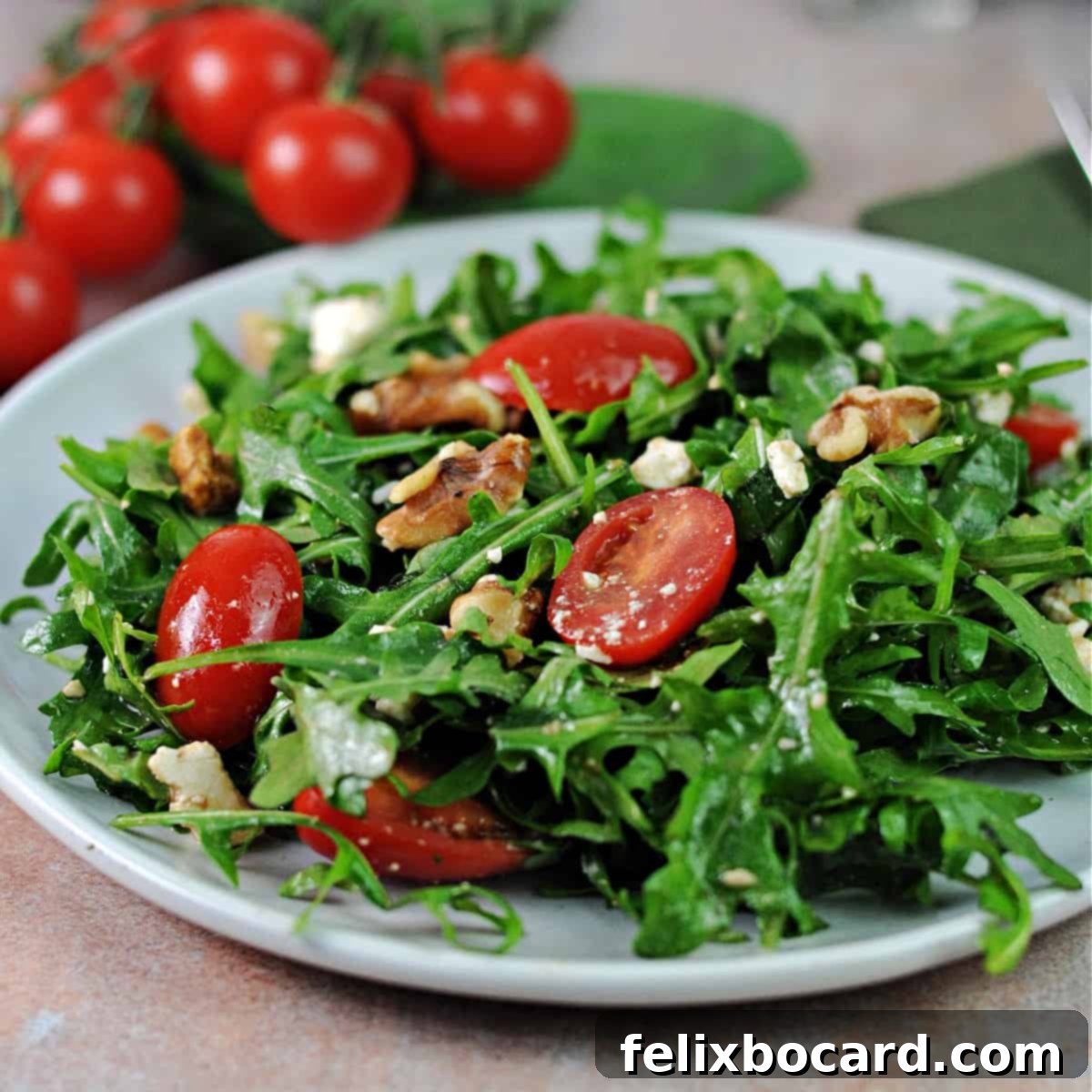 A vibrant serving of Arugula Feta Tomato Salad on a small white plate, showcasing its fresh ingredients.