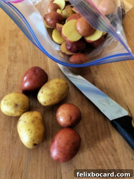 Halved baby potatoes being placed into a plastic bag with olive oil
