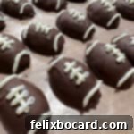 Many decorated football Oreo truffles on wax paper, ready to be served.