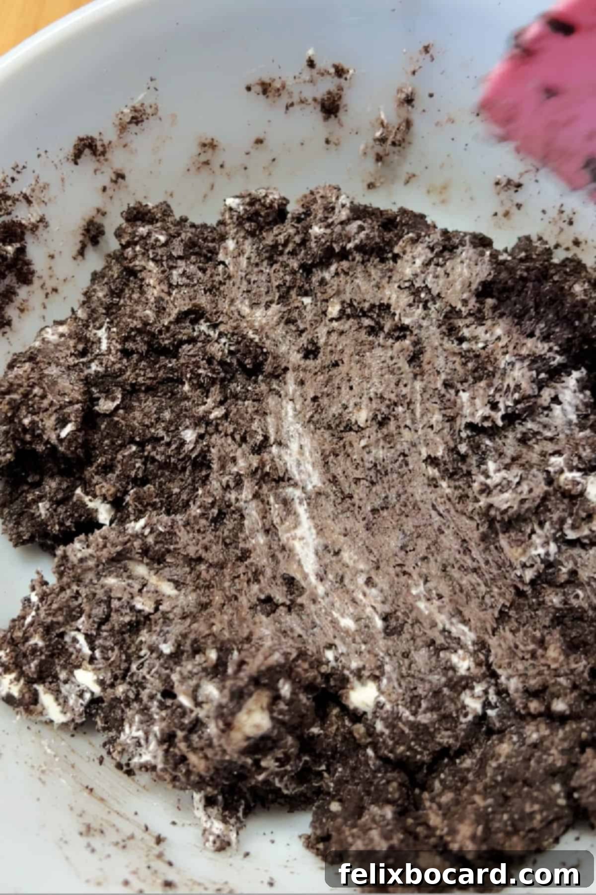 Mixing crushed Oreo cookies and softened cream cheese in a bowl to form the truffle mixture.