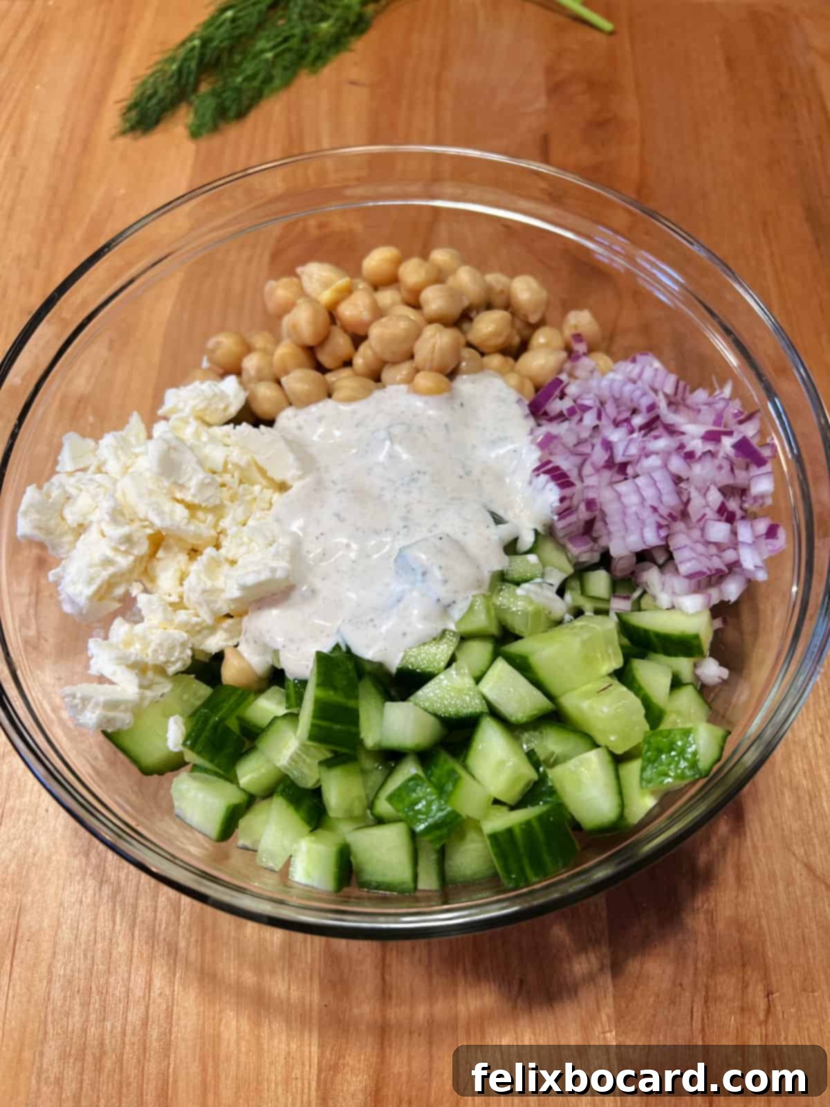 Dressing poured over salad ingredients in a bowl, ready to be tossed.