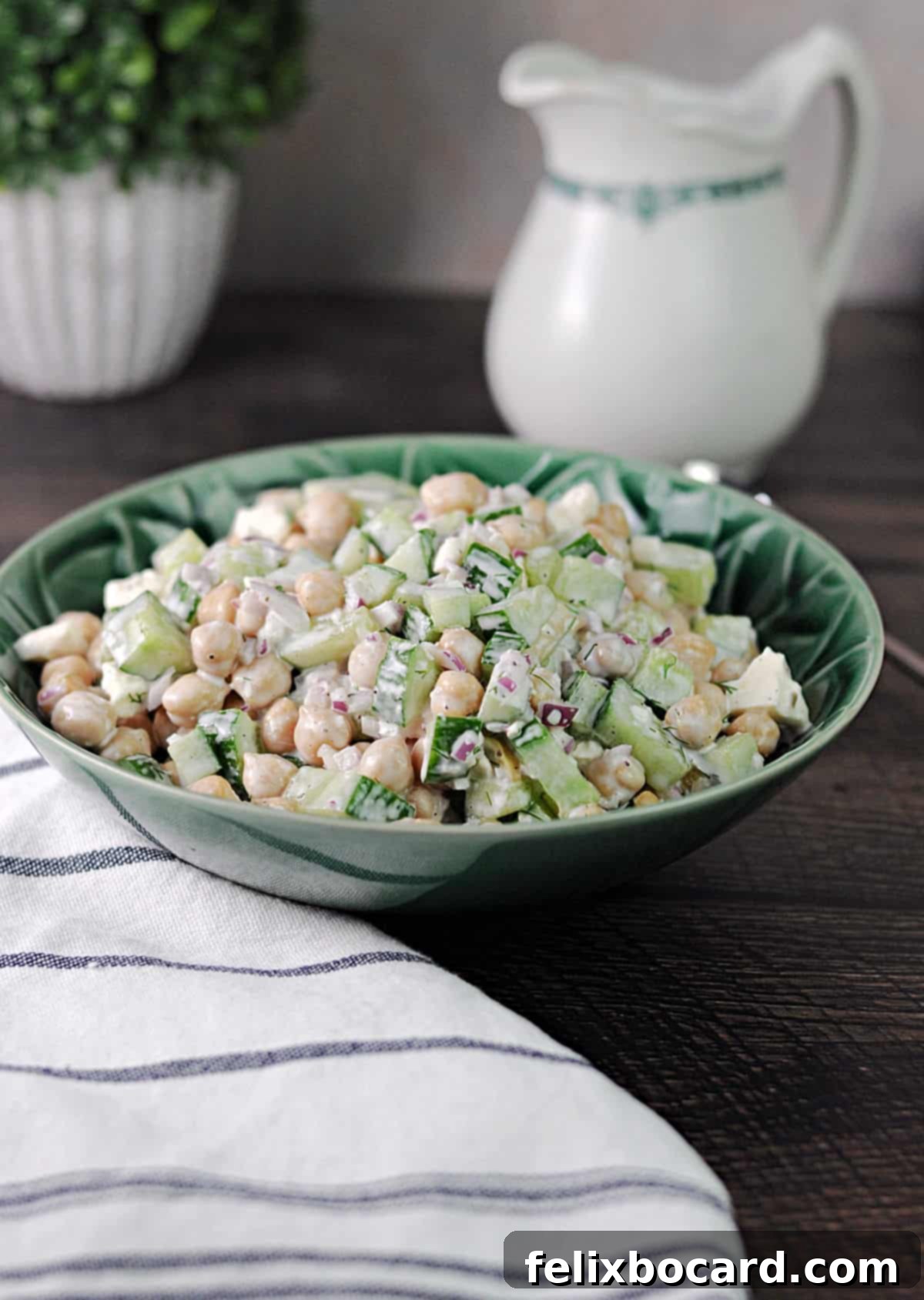 A green serving bowl of cucumber chickpea salad with feta and fresh dill.