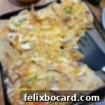 A tray of perfectly cooked air fryer nachos, garnished with fresh cilantro and ready to be served with a spatula.