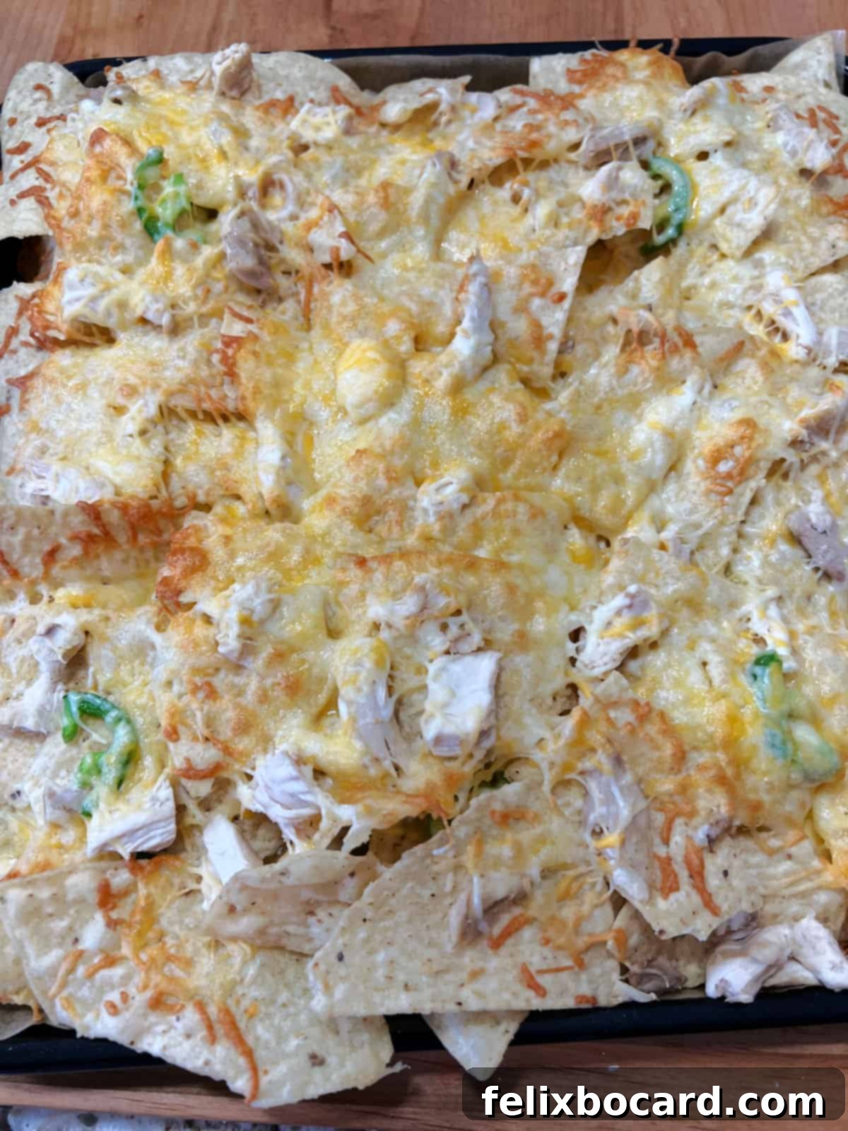 A tray of freshly cooked, golden-brown nachos with melted cheese and toppings, just removed from the air fryer.