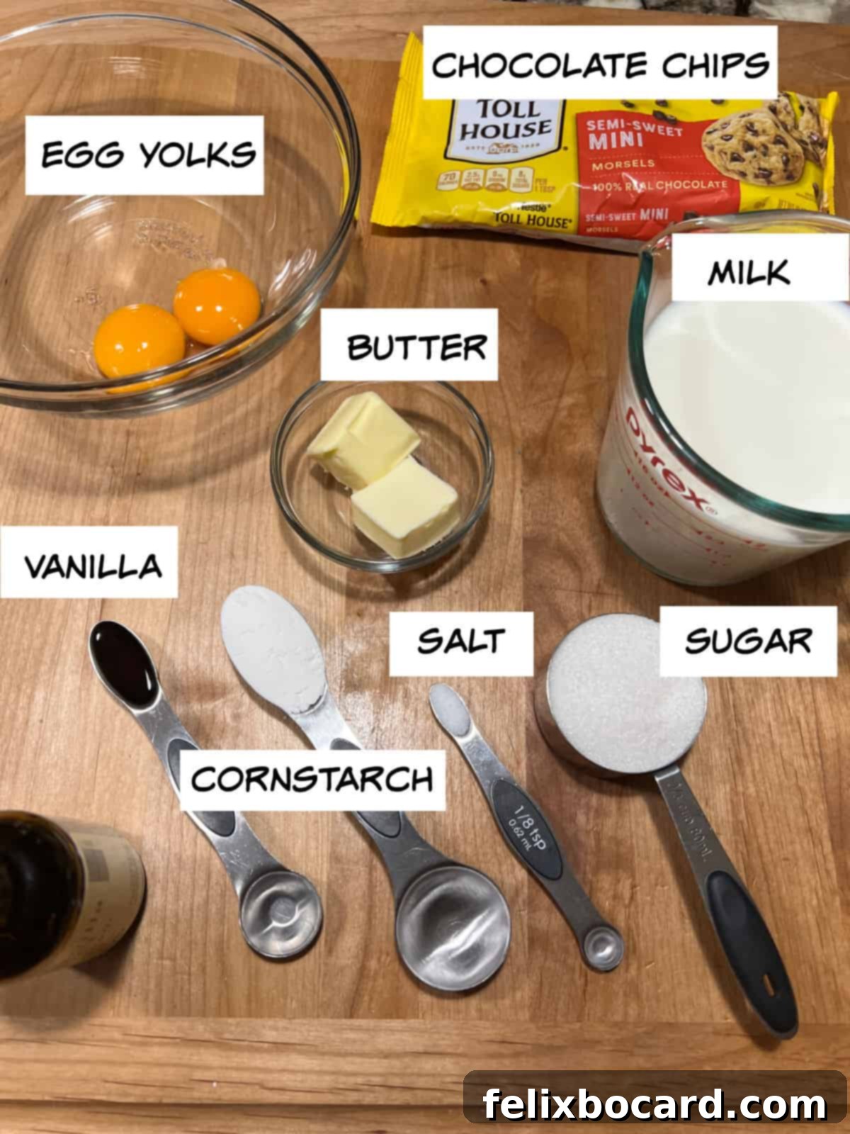 Ingredients: egg yolks, chocolate chips, milk, butter, sugar, salt, cornstarch, vanilla beautifully arranged on a rustic wooden board.