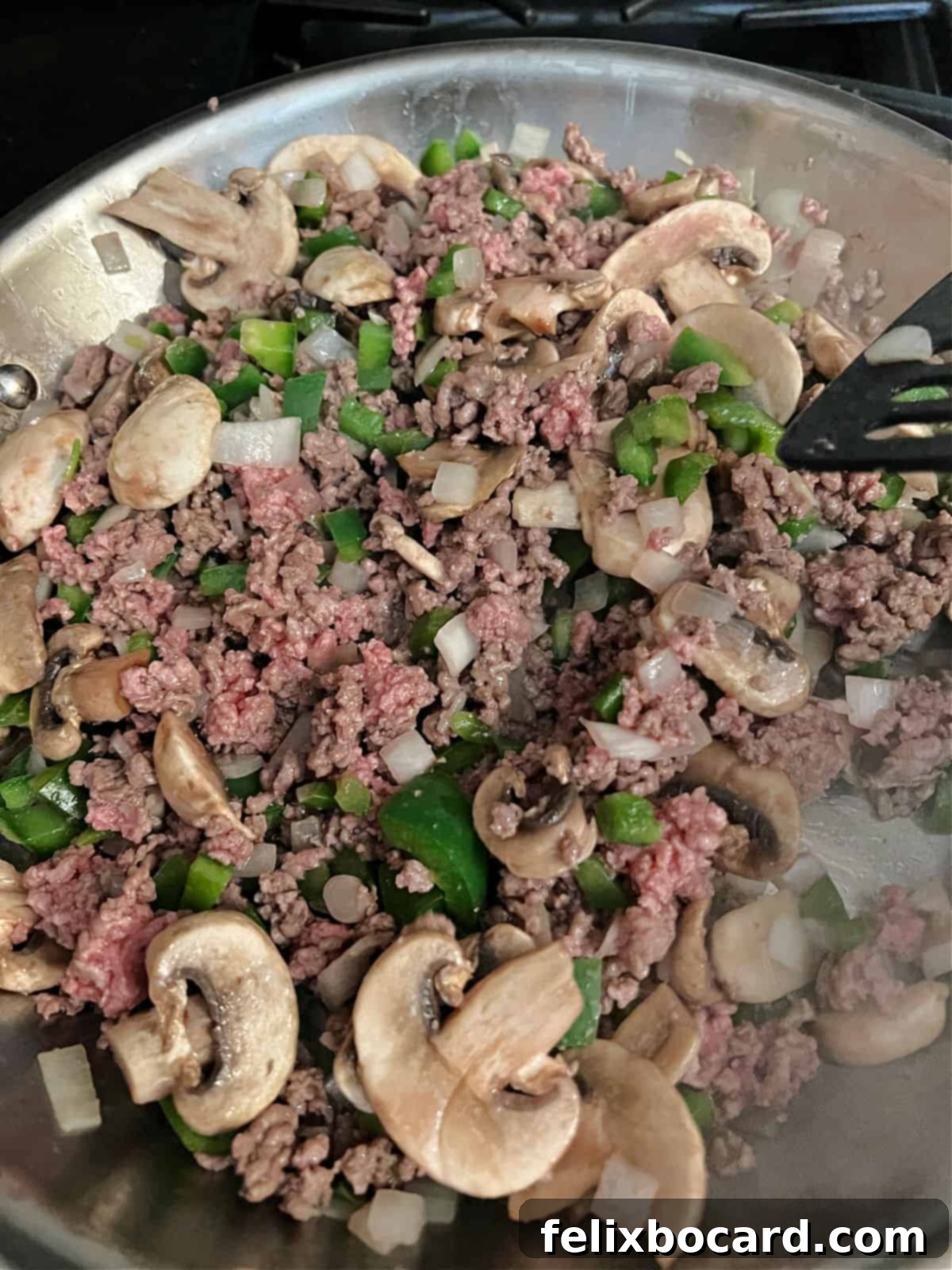 Sautéed ground beef, green bell pepper, onion, and mushrooms cooking in a large skillet, ready for the next steps of the Philly Cheesesteak Casserole recipe.