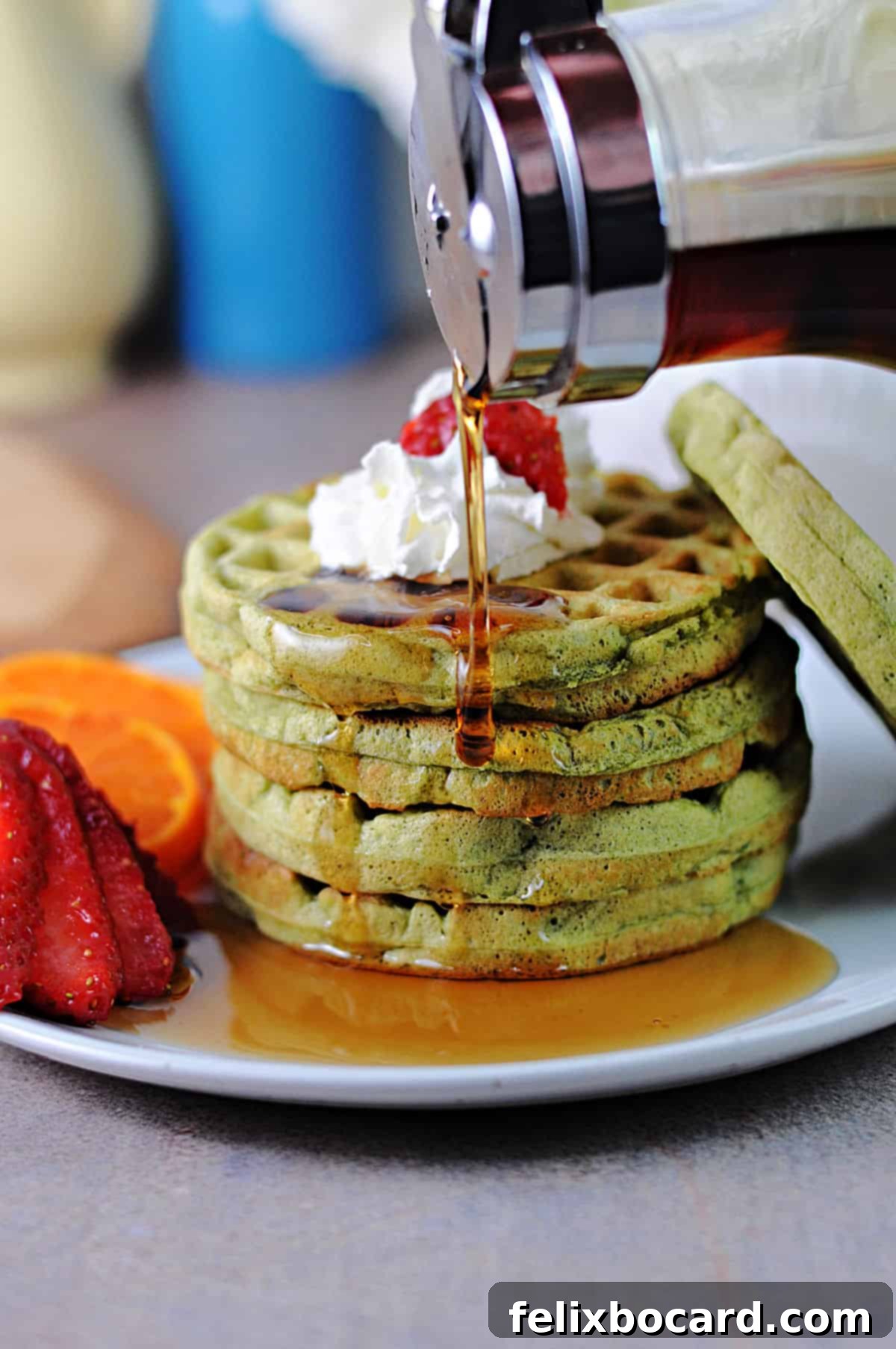 Stack of fluffy matcha waffles with maple syrup drizzled onto the edge, showcasing their vibrant green color and perfect texture.