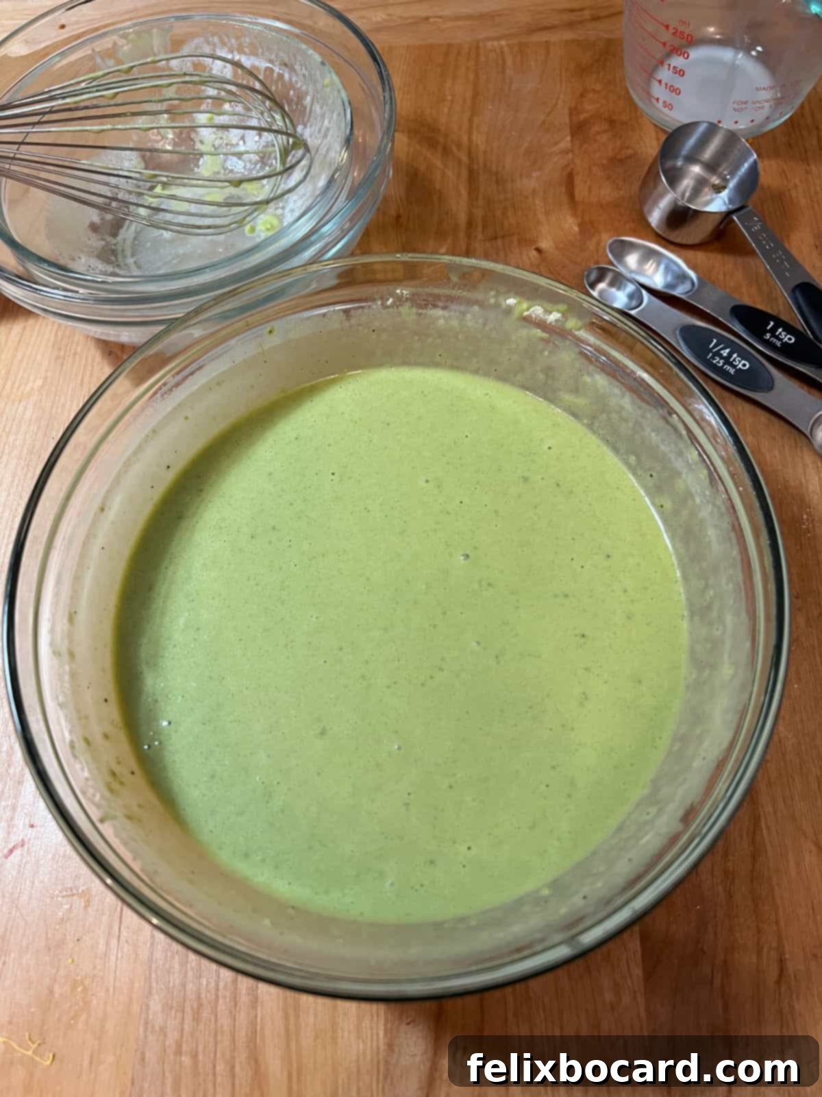 Smooth, vibrant green matcha waffle batter in a large mixing bowl, perfectly blended and ready to be cooked.