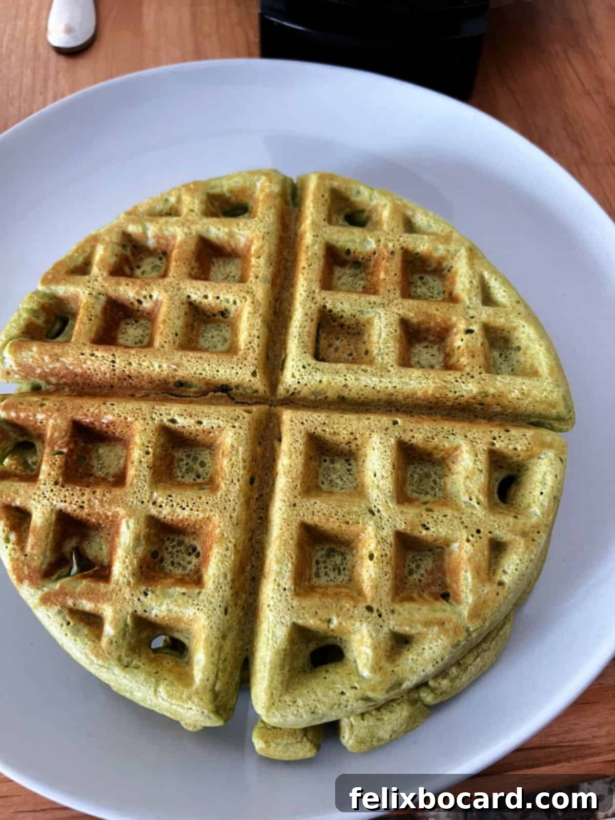 A perfectly cooked standard-sized matcha waffle resting on a white plate, ready for delicious toppings.