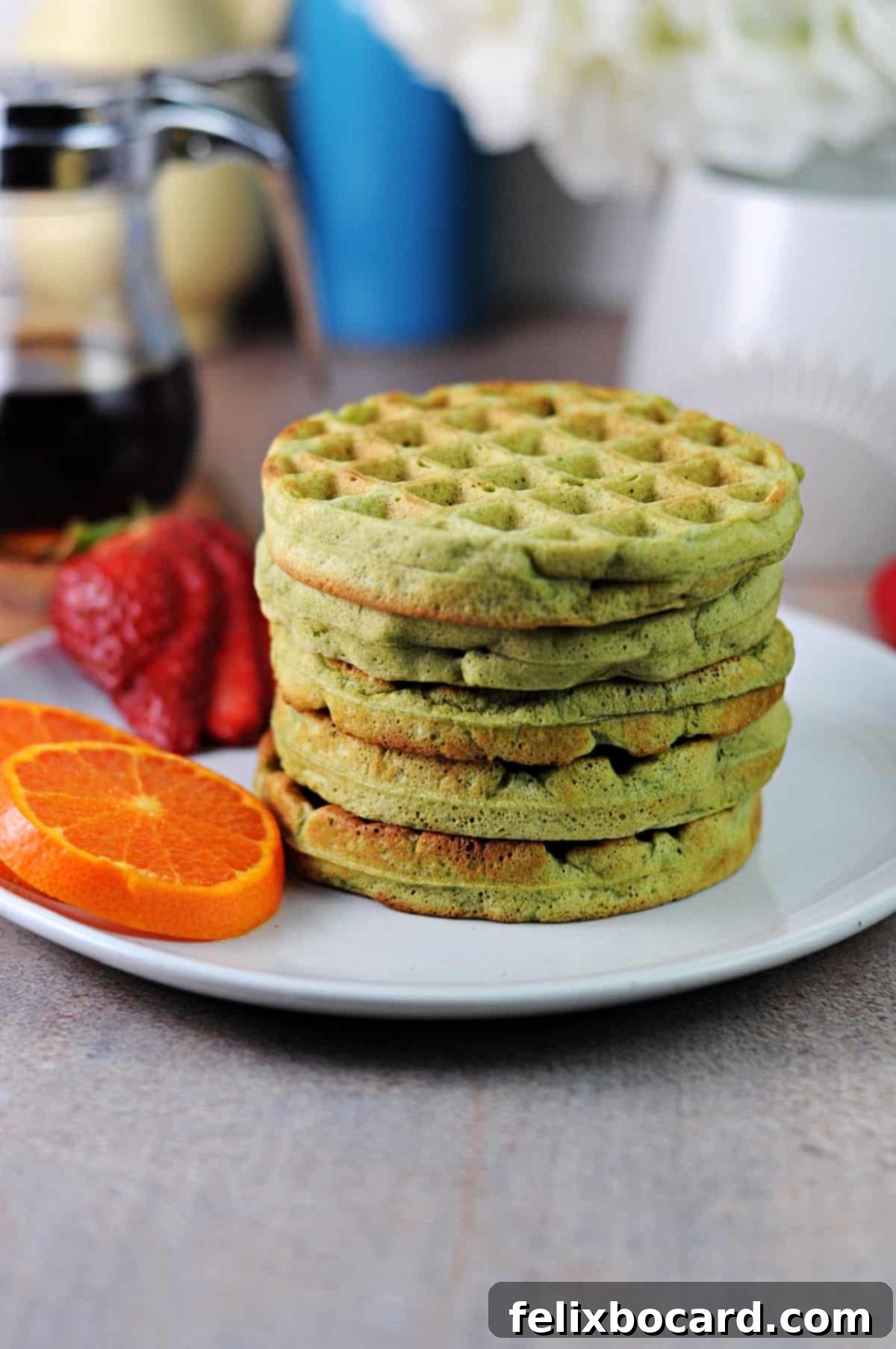 A stack of small, perfectly cooked matcha waffles, showcasing their fluffy interior and light green color.