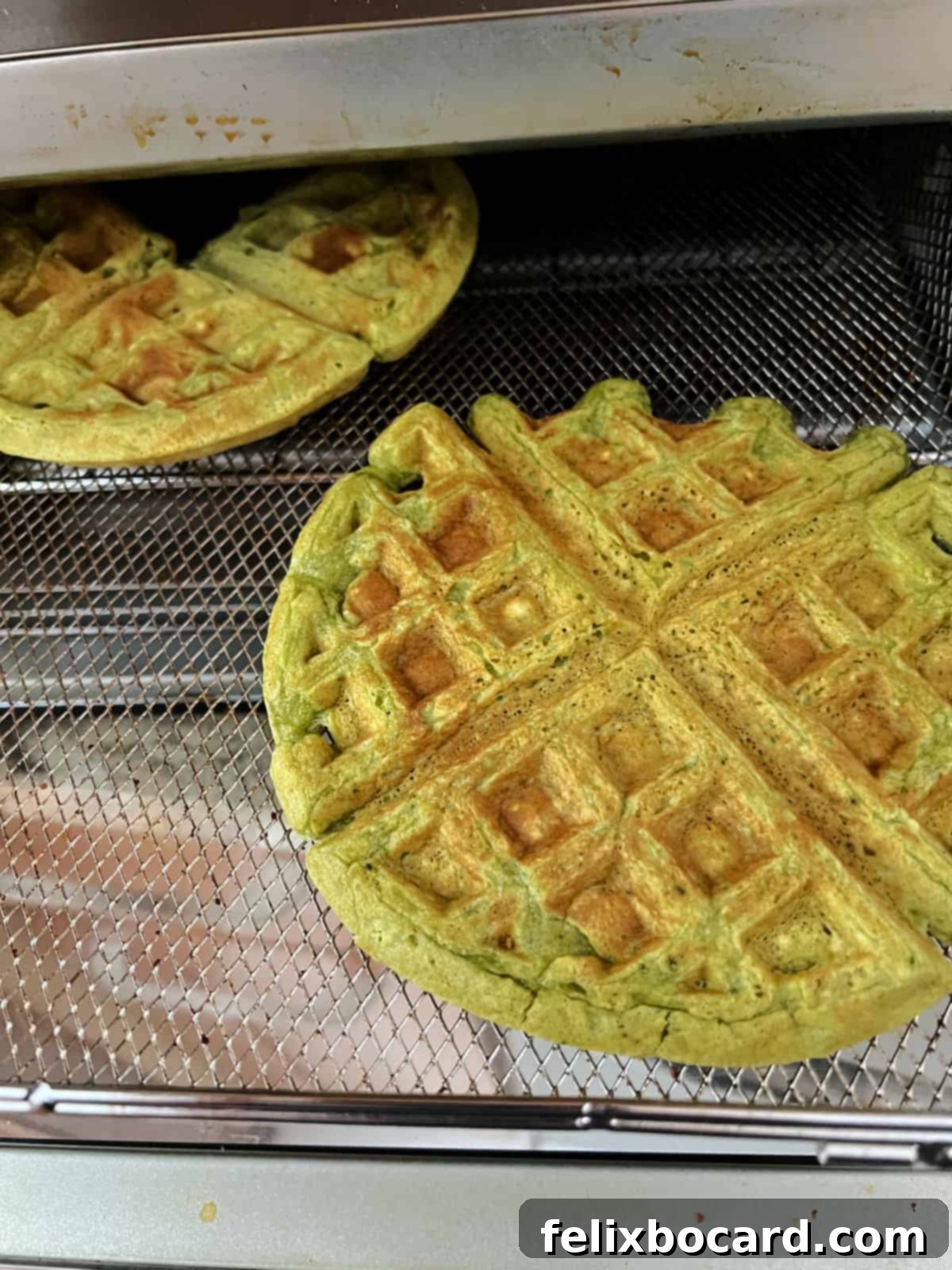 Matcha waffles being re-crisped in an air fryer basket, showing their transformation back to a crispy texture.