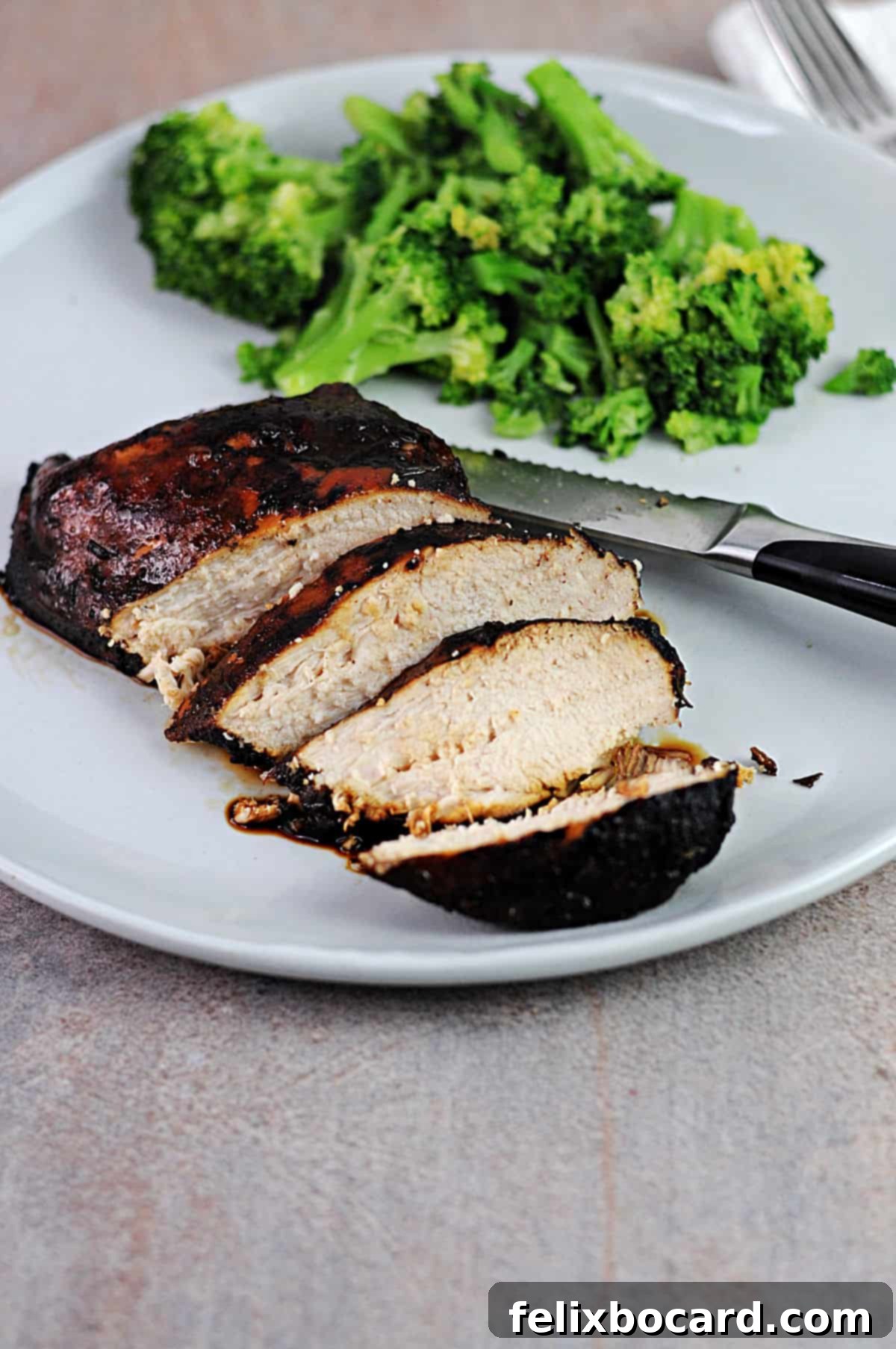 balsamic rosemary chicken breast sliced on a plate with some broccoli.