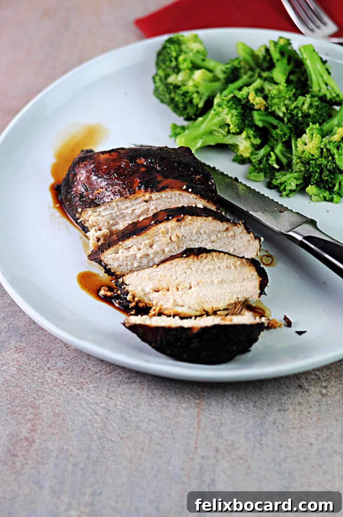 sliced balsamic chicken breast on a plate with broccoli.
