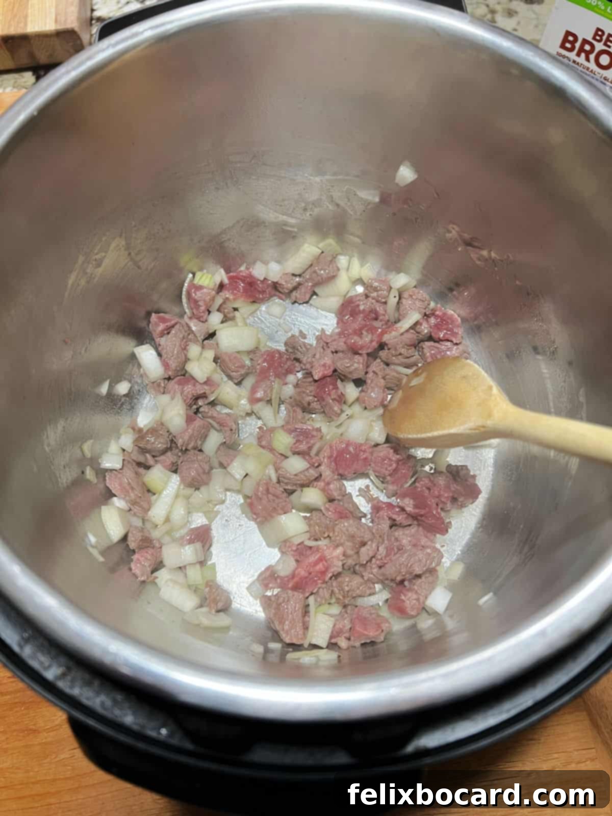 Effortless Instant Pot Beef & Vegetable Soup 5 Beef stew meat and chopped onion being sautéed in the Instant Pot.