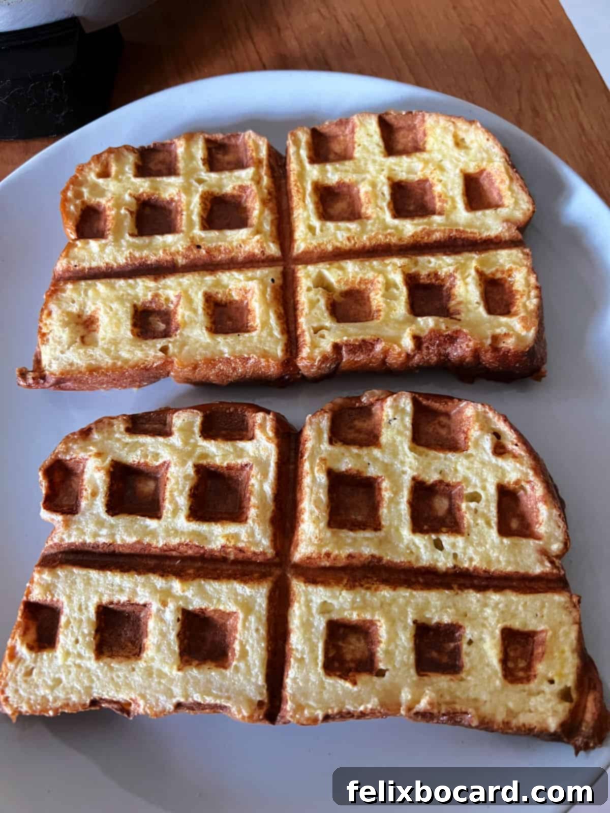 Two perfectly cooked, golden-brown French toast waffles on a plate.