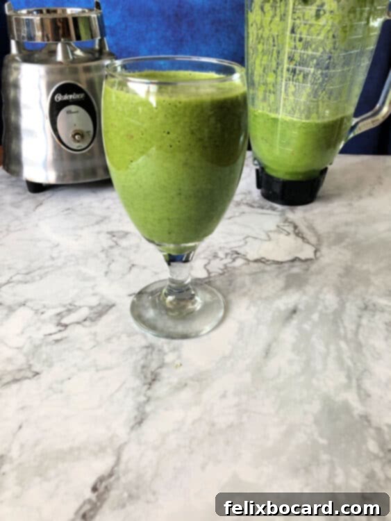 Daily Green Boost 2 green smoothie in a glass with blender behind