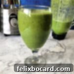 Daily Green Boost 6 glass of green smoothie with blender behind