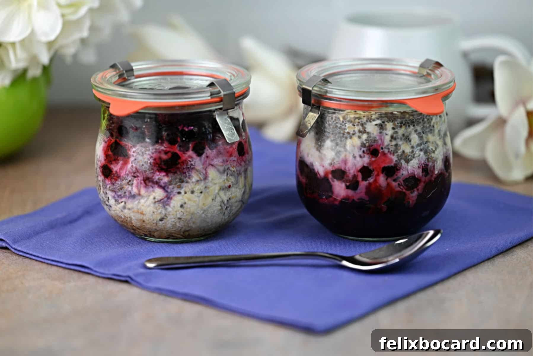 Two jars of overnight oats, one with fruit layered on top, the other with fruit on the bottom, ready for consumption.