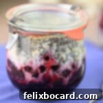 Jar of layered overnight oats with frozen fruit on the bottom, ready to be refrigerated.