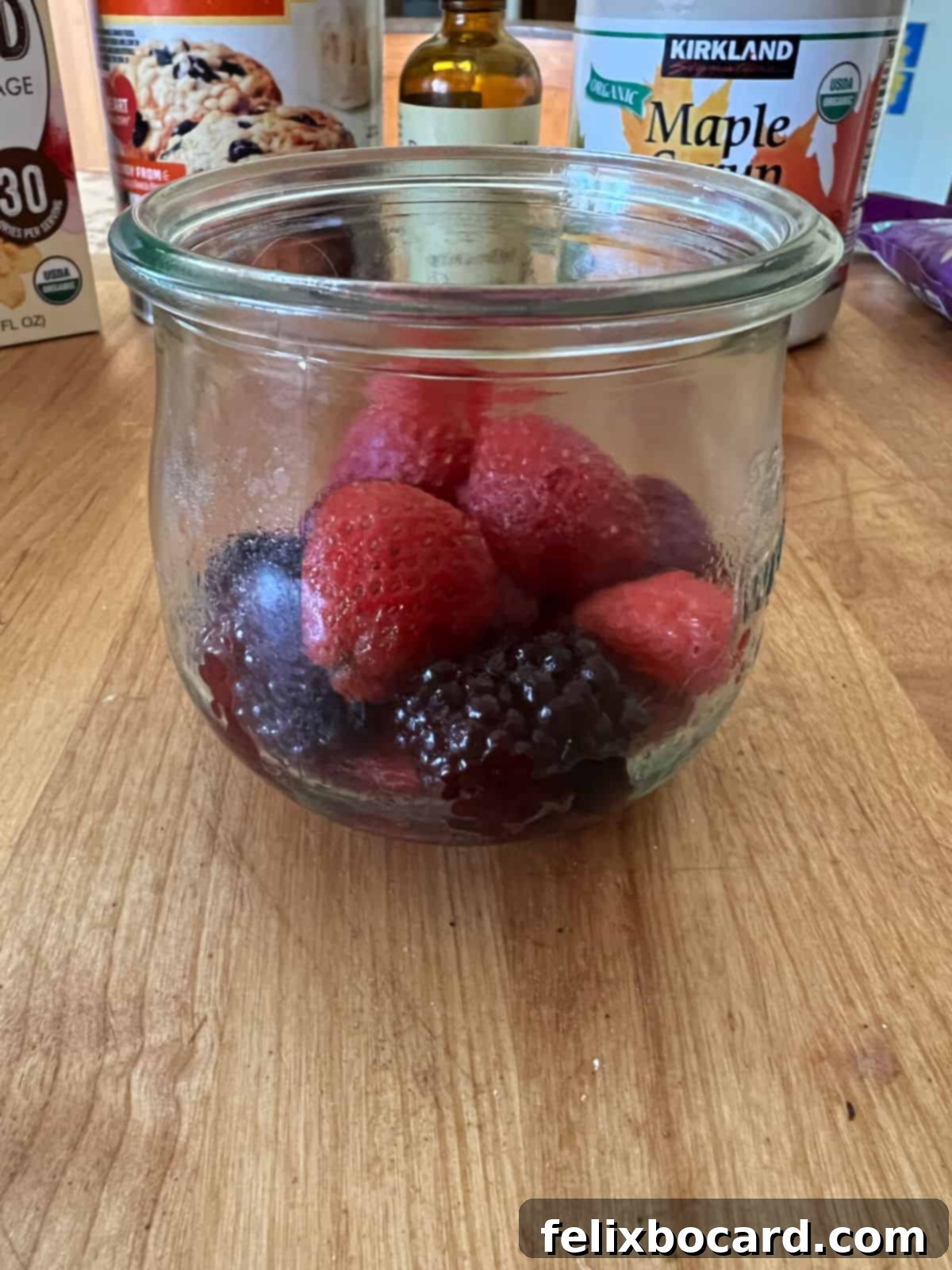 Thawed berries placed in the bottom of a glass jar, ready for mashing.