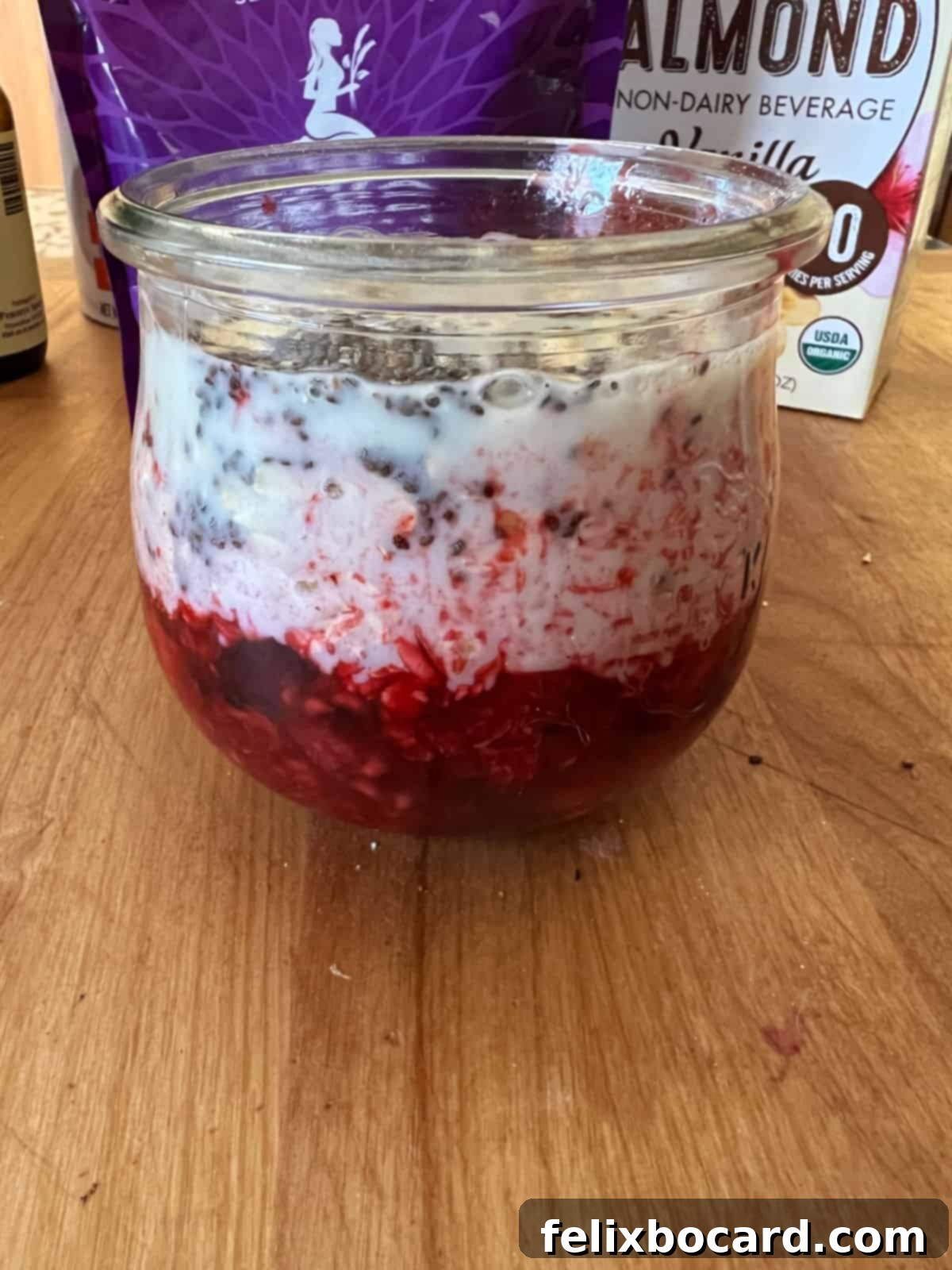 All ingredients, including mashed fruit, maple syrup, vanilla, oats, chia seeds, and almond milk, are layered in a glass jar without being stirred.