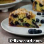 slice of blueberry sour cream coffee cake on a plate, ready to eat.