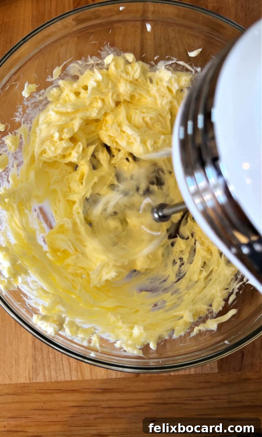 Electric mixer creaming butter, sugar, and lemon zest in a bowl.