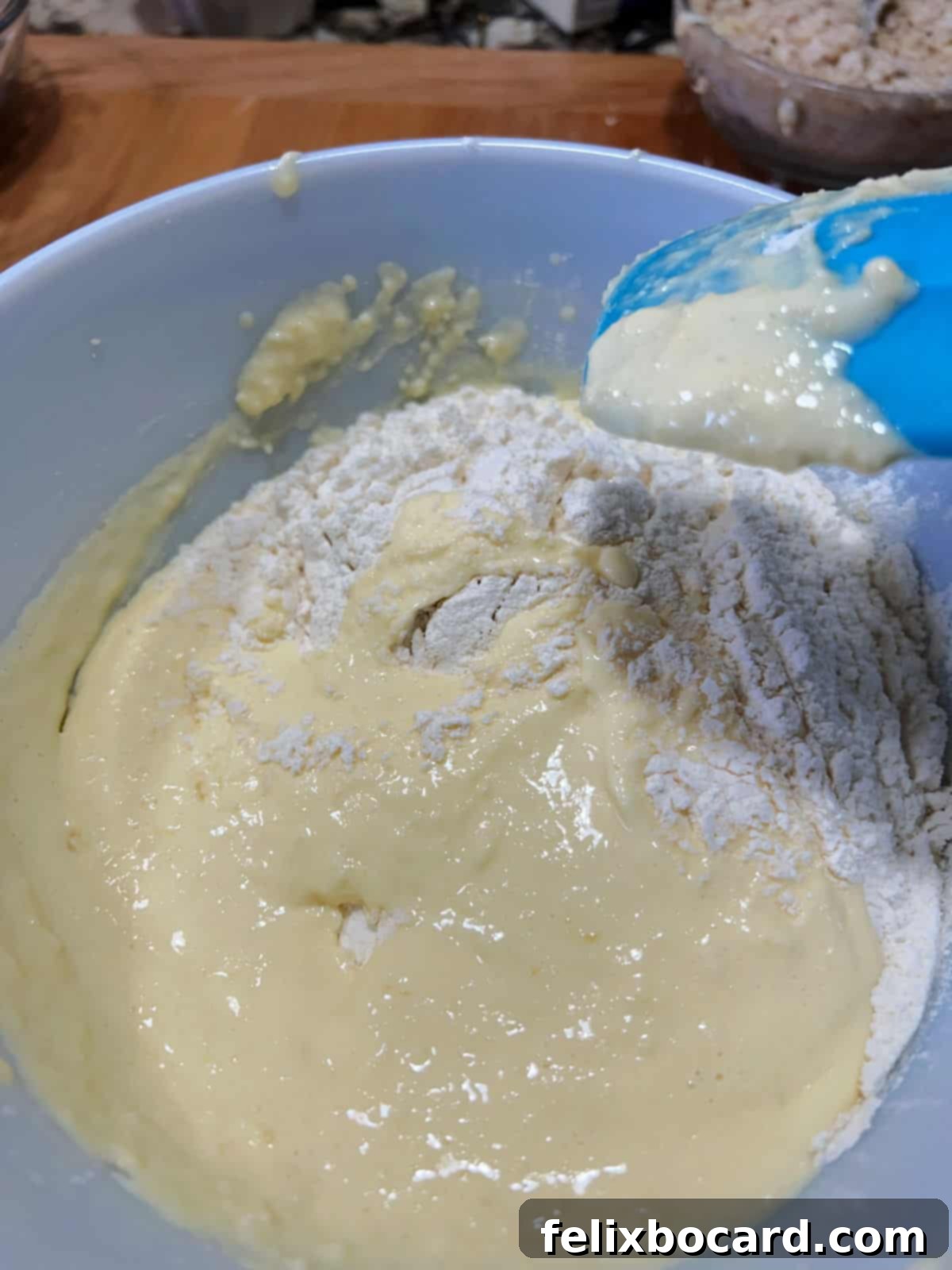 A spatula stirring dry ingredients into the wet batter.