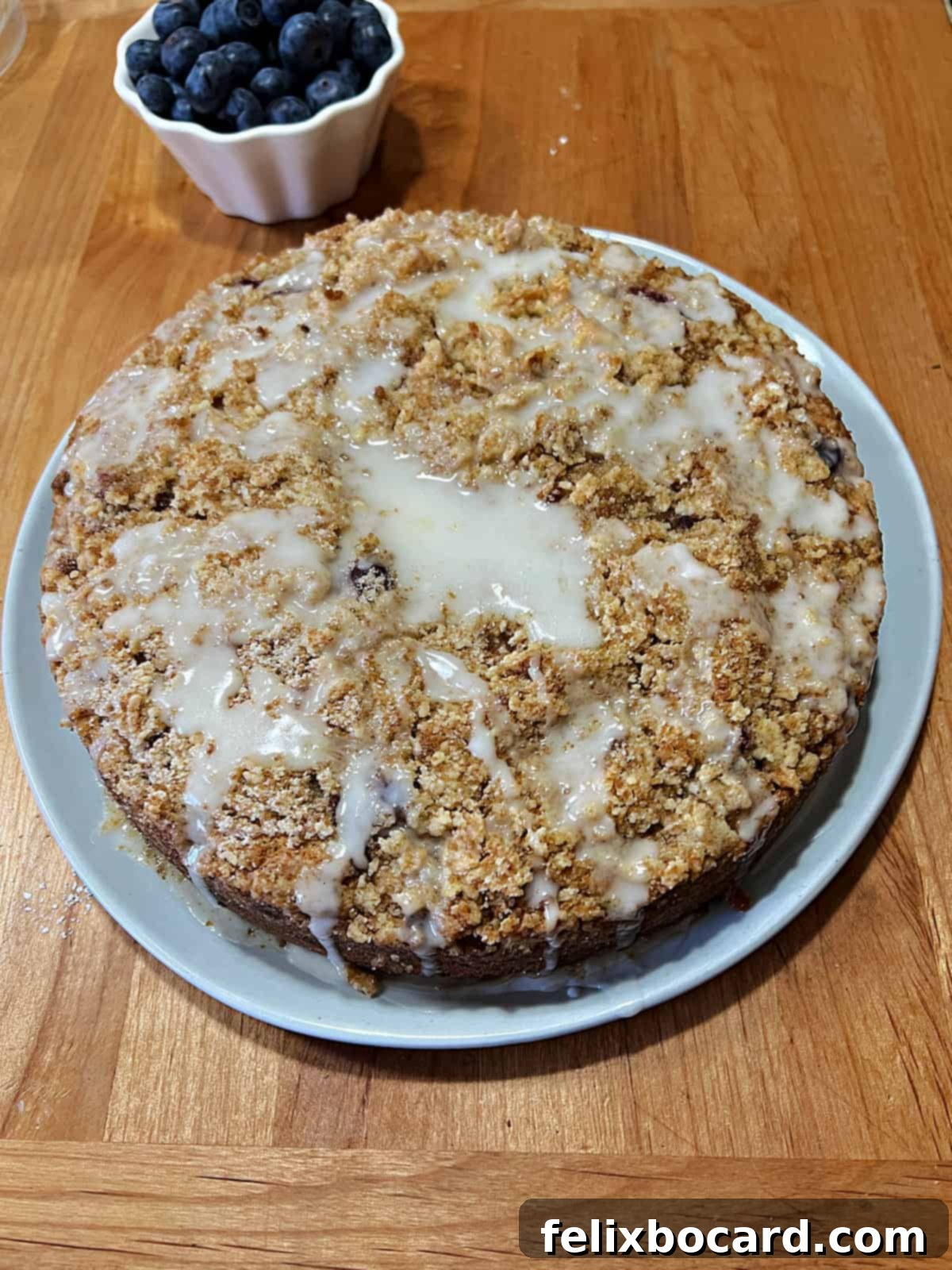 A freshly baked blueberry sour cream coffee cake, beautifully glazed and ready to slice.