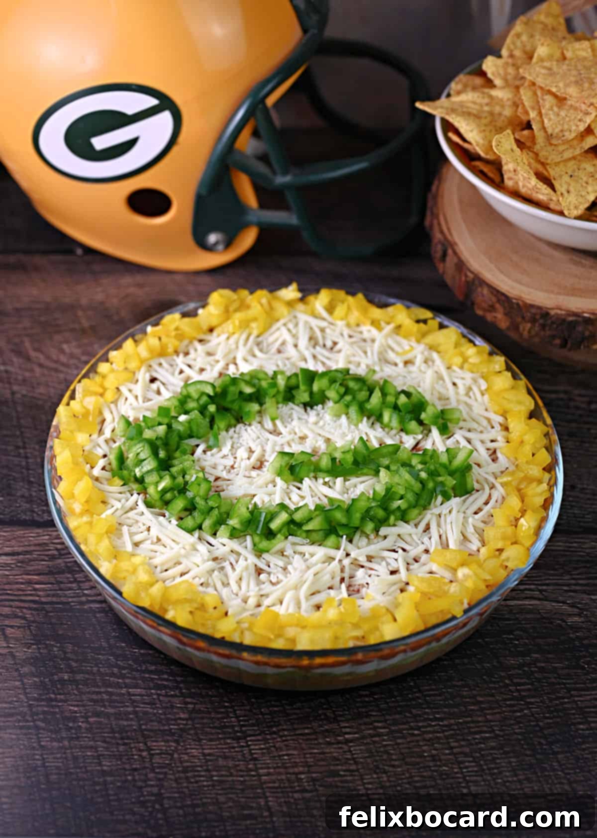 A vibrant Layered Taco Dip featuring the Green Bay Packers logo, surrounded by tortilla chips, ready for guests to enjoy at a football party.