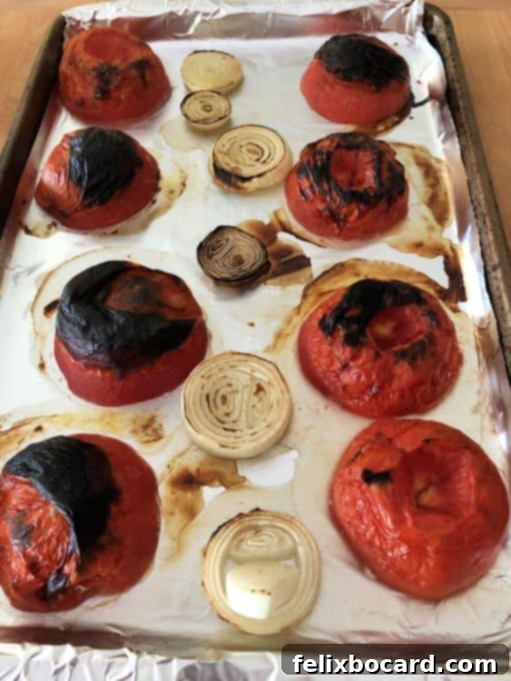 roasted tomatoes and onions on a baking sheet for salsa