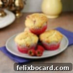 Three raspberry white chocolate muffins on a small plate, ready to eat.