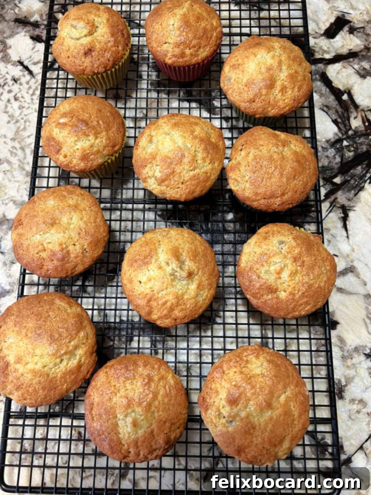 A close-up of freshly baked golden-brown banana bread muffins cooling on a metal wire rack, releasing steam and promising a delicious treat.