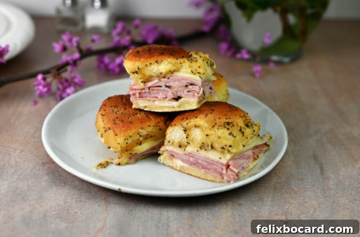 Hawaiian Ham and Cheese Sliders 2 Three golden brown ham and cheese air fryer sliders on a small white plate, garnished and ready to eat.