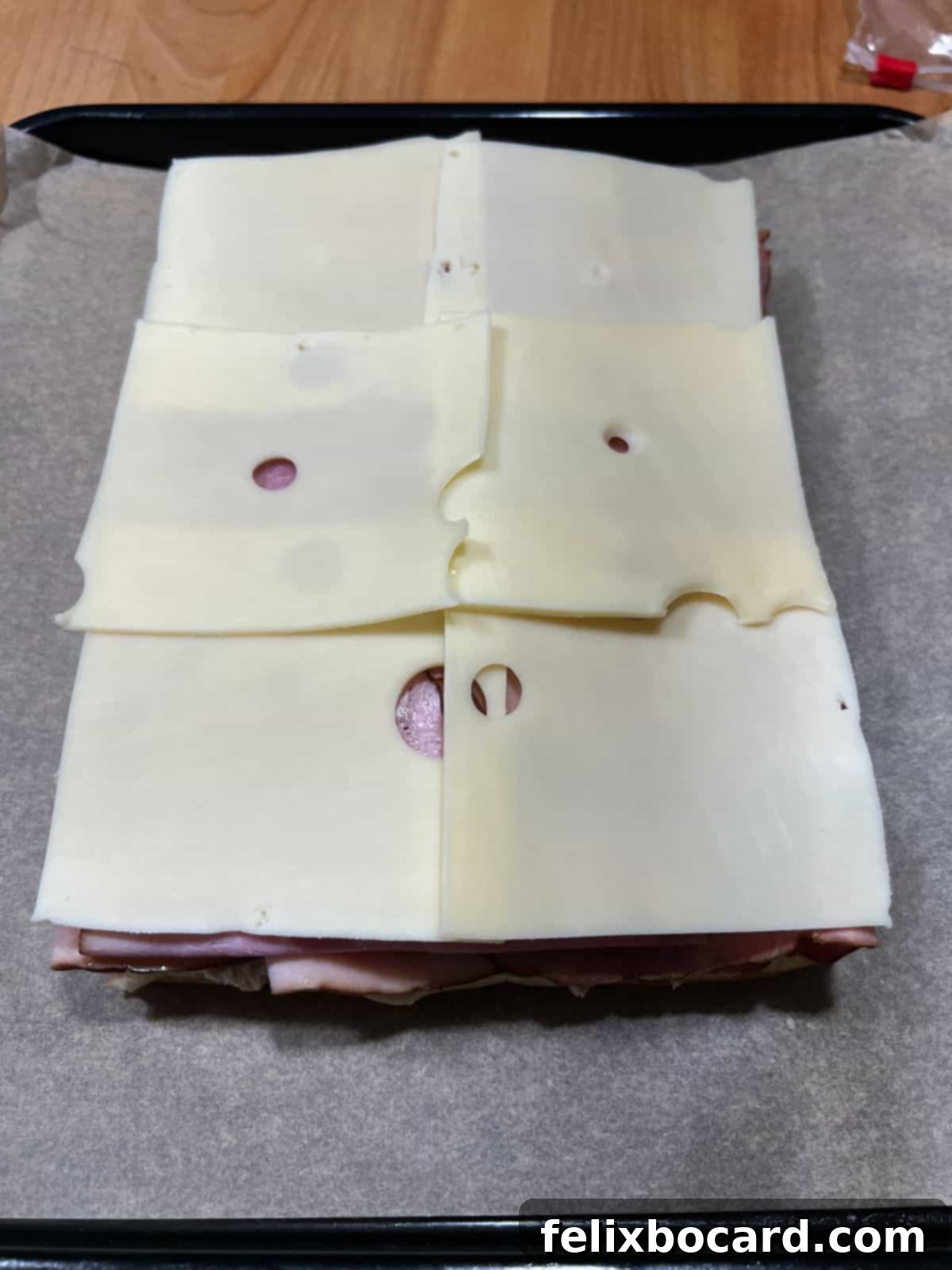 Hawaiian Ham and Cheese Sliders 5 The bottom layer of dinner rolls covered with alternating layers of ham and Swiss cheese, ready for the top bun.