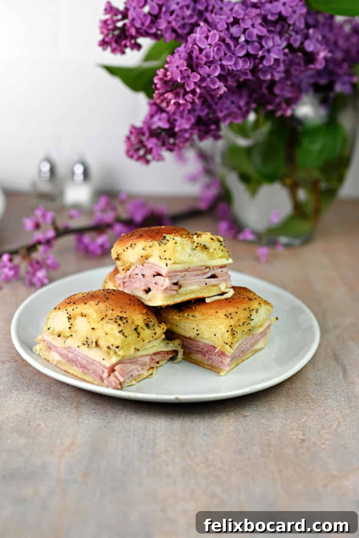 Hawaiian Ham and Cheese Sliders 7 Three perfectly stacked Ham & Cheese Sliders on a rustic white plate, ready to be enjoyed.
