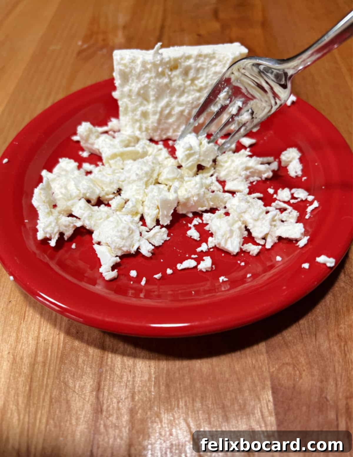 Breaking up a block of feta cheese with a fork.