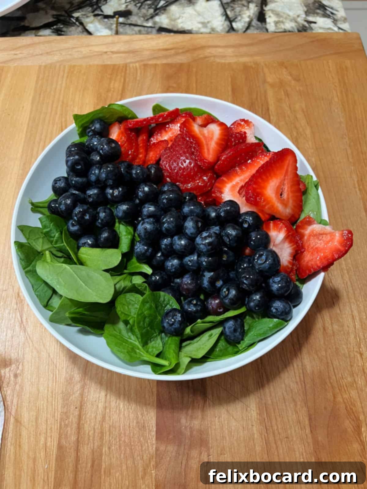 Spinach, blueberries, and strawberries in a bowl.